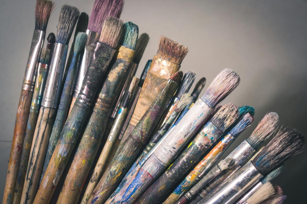 A painting in progress on an easel, with brushes and paints scattered around